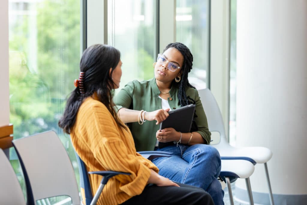 A female counselor listens to female client seated beside her