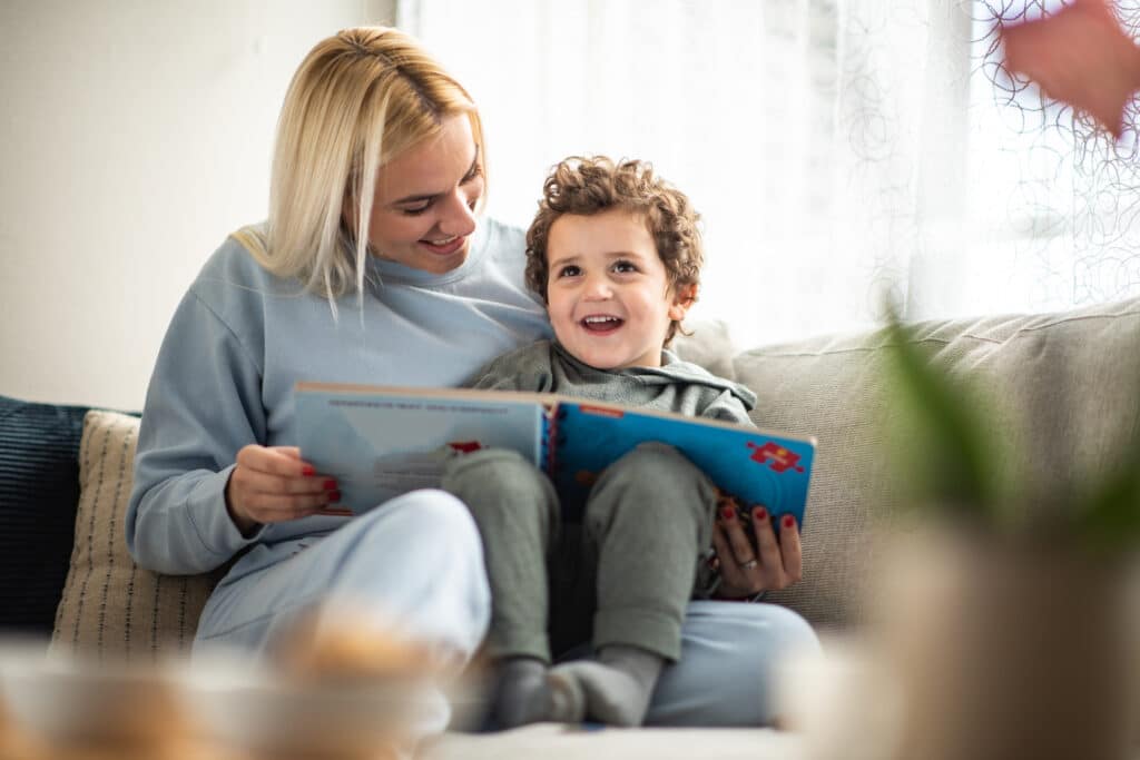 Preschool boy reading book with mother