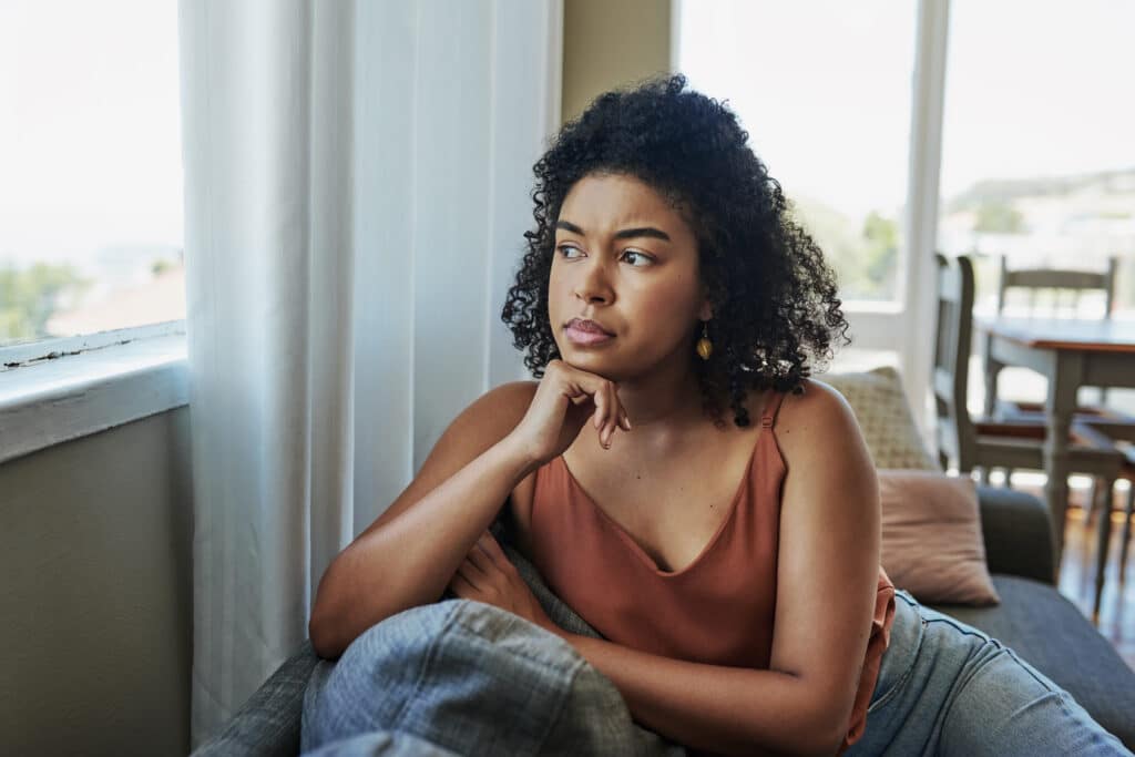 a young woman looking pensively out a window at home