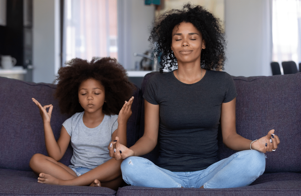 Mother and daughter sitting on couch in meditative pose